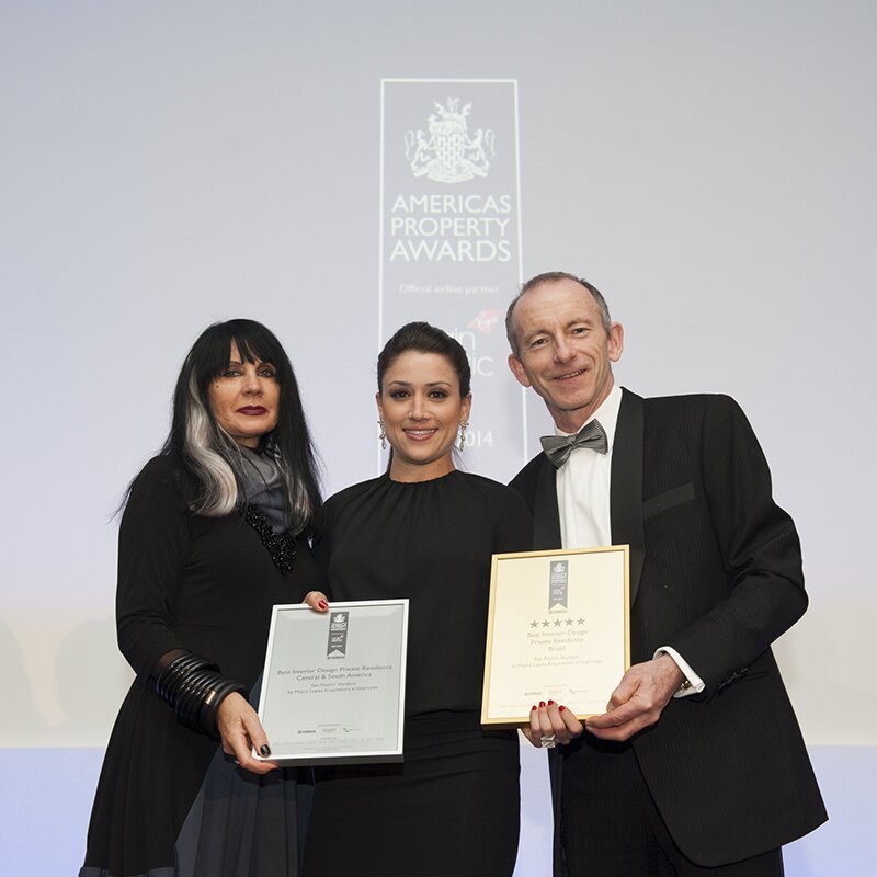 Mayra Lopes no palco da cerimônia do Americas Property Awards, recebendo os dois certificados de Best Interior Design — Private Residence
